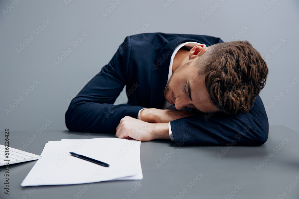 handsome businessman drinking coffee tired at work with documents on the table Gray background handsome businessman drinking coffee tired at work with documents on the table Gray background
