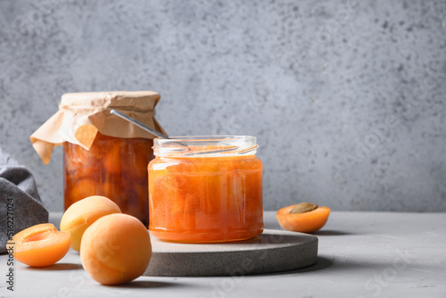 Homemade Apricot jam in glass jar on kitchen white background. Summer harvest and canned food for winter. Tasty dessert. Copy space.