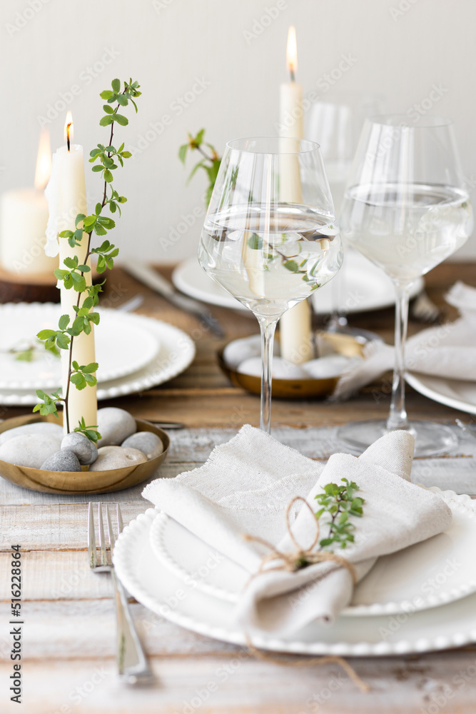 Rustic zero waste wedding decor with natural elements. Wooden table, candles, linen napkins, branches with green leaves. Eco-friendly decoration for the special dinner. Romantic and cozy place