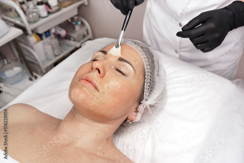 Moisturizing rejuvenation facial peeling mask. Medicine and cosmetology. Beautician's hands in black gloves do facial massage and peeling at the spa salon. Skin and body care, spa beauty treatment.