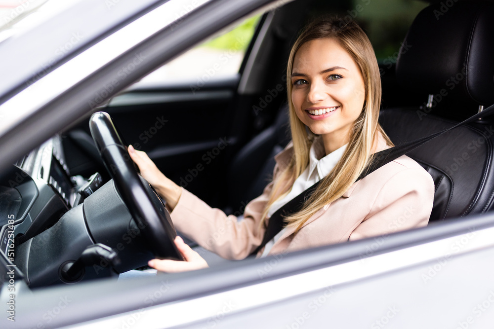 Young beautiful smiling woman fass belt and driving a car.