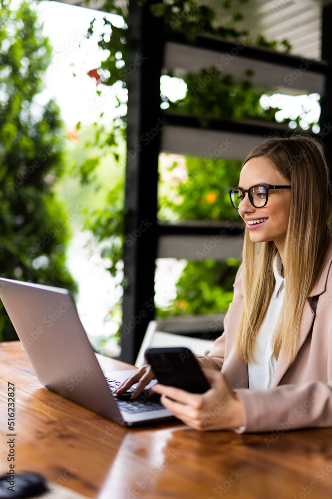 Portrait of a young woman holding and using phone and laptop computer in cafe Portrait of a young woman holding and using phone and laptop computer in cafe