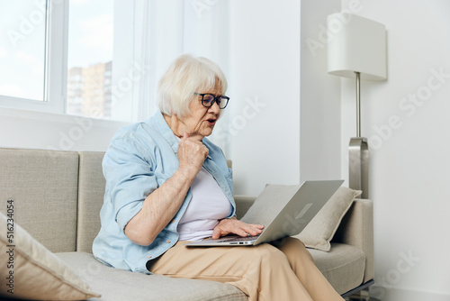 an elderly lady looks at a laptop monitor showing her fist while talking via video link while at home