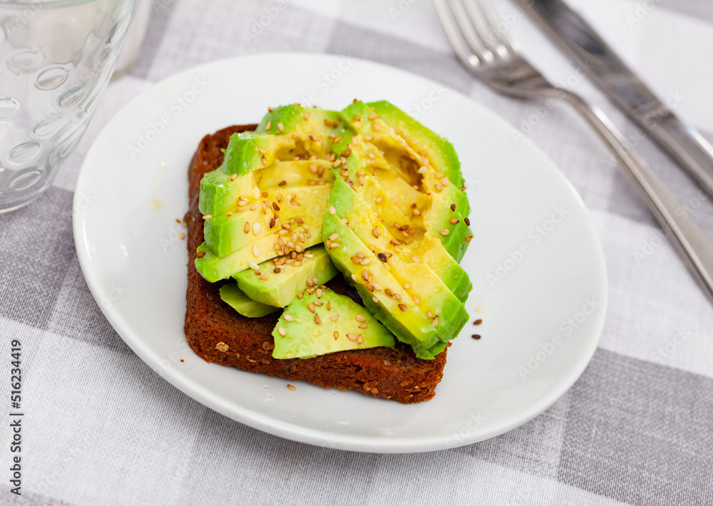 Tasty avocado toasts on white plate closeup