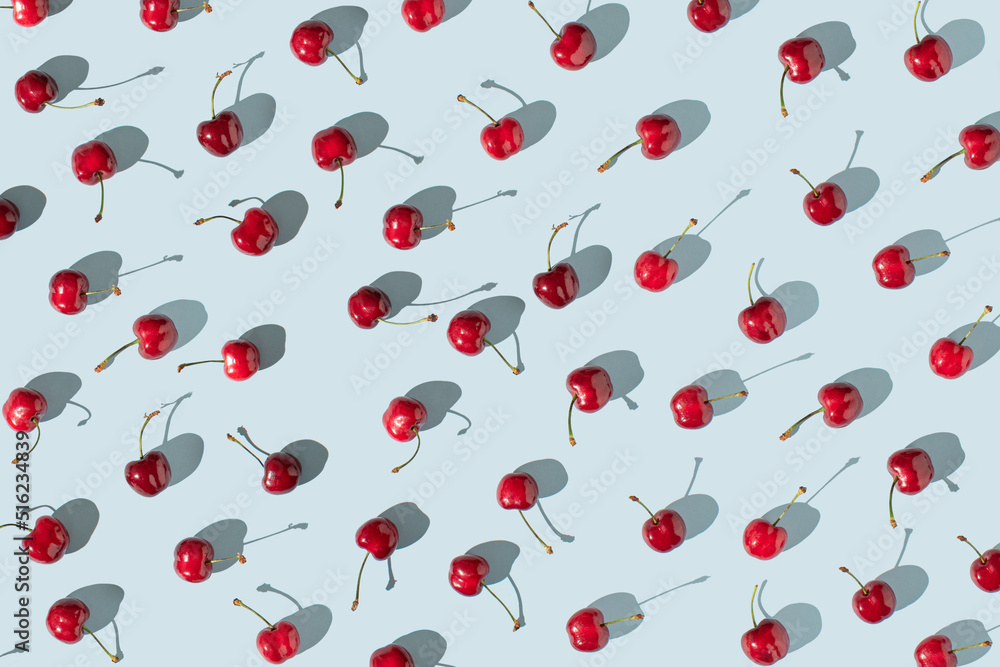 Red cherry fruits on sunny blue background. Creative summer fruits pattern concept. Red cherry fruits on sunny blue background. Creative summer fruits pattern concept.