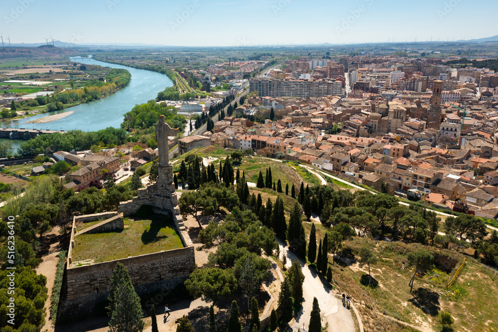 Scenic aerial view of Tudela cityscape on Ebro river from Cerro del Castillo with Monument to Sacred Heart of Jesus erected on hilltop on main tower of ruined castle on spring day, Navarre, Spain
