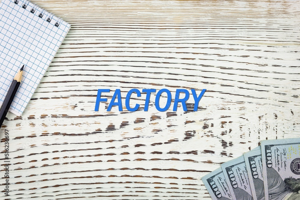 Naklejka premium FACTORY - word (text) and dollars on a white wooden table, notebook, notepad. Business concept: buying, selling, commerce (copy space).