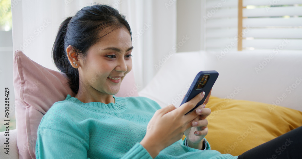 Young attractive beautiful casual asia female lady or student look at cellphone play social media IG reel tiktok app lying down at sofa couch living room feel relax comfort carefree at home apartment. Young attractive beautiful casual asia female lady or student look at cellphone play social media IG reel tiktok app lying down at sofa couch living room feel relax comfort carefree at home apartment.