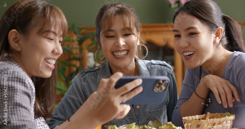Small girl group party asia people busy talk smile eat brunch food drink. Young woman fun happy hour meal shoot photo of dish plate salad bowl on table post ig reel story app in vegan cafe bar shop.