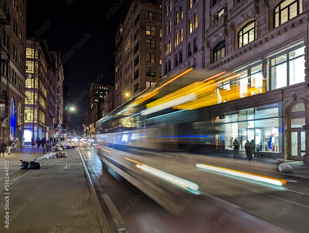 Blurred lights of a bus driving down Broadway through New York City at night

