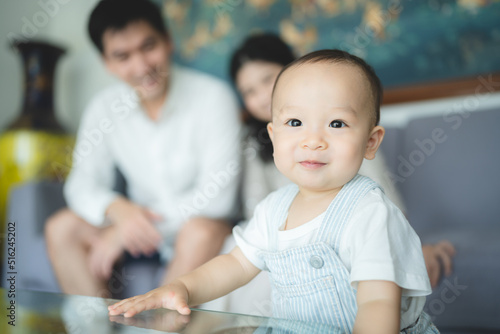 Playful young mother playing with toddler baby sitting on father lap on couch at home