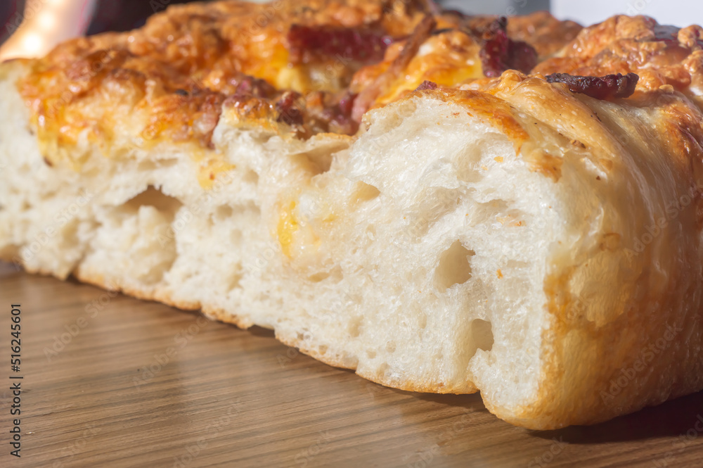 Freshly baked italian foccacia with yellow cheese and pastrami,in a wooden tablet with copy space left