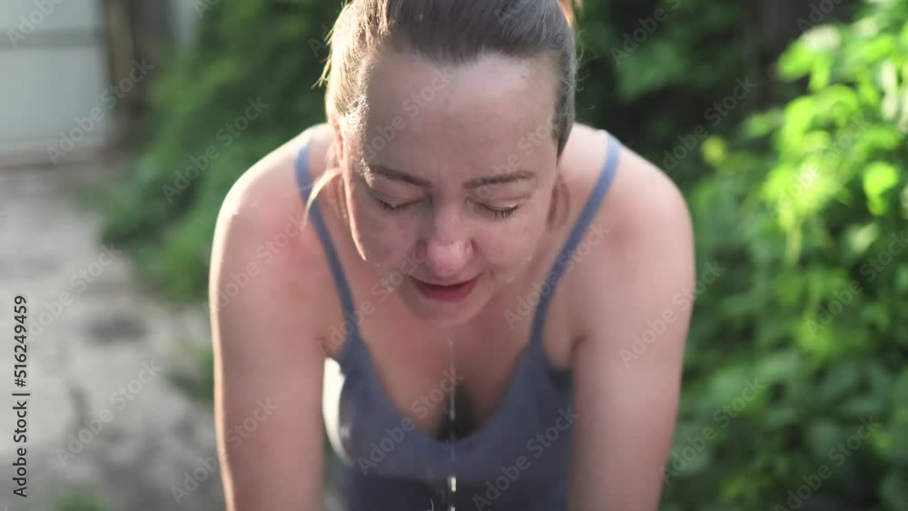 Middle age woman washing her face in sunlight Middle age woman washing her face in sunlight