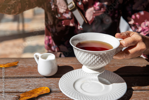 female hand holding a hot cup of tea in autumn morning