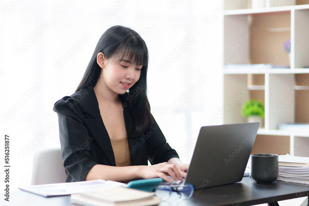 Beautiful Asian business woman is using a laptop to work in the office with a cheerful expression. Beautiful Asian business woman is using a laptop to work in the office with a cheerful expression.