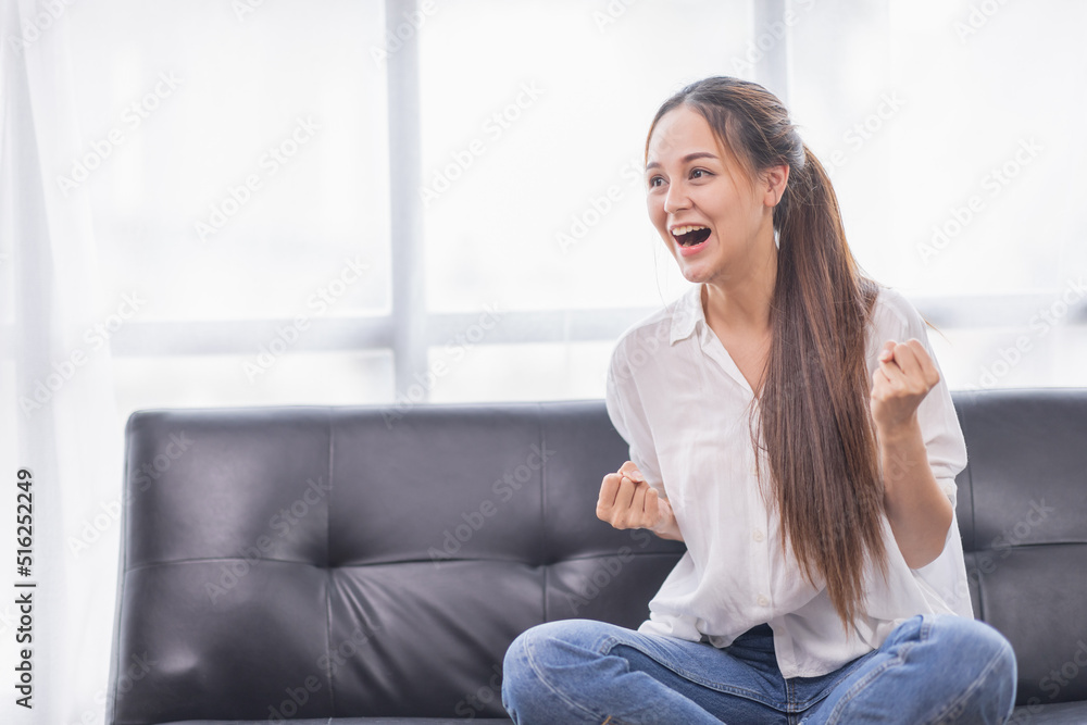 Excited young Asian woman on sofa in home office Excited young Asian woman on sofa in home office