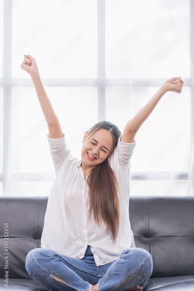 Excited young Asian woman on sofa in home office