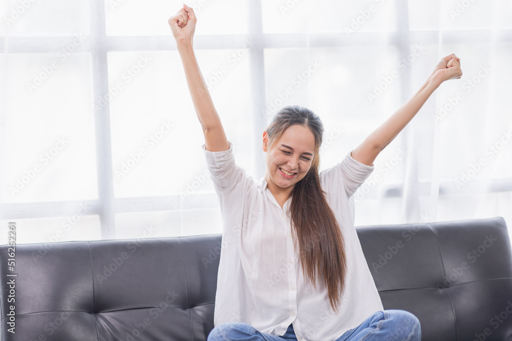 Excited young Asian woman on sofa in home office Excited young Asian woman on sofa in home office