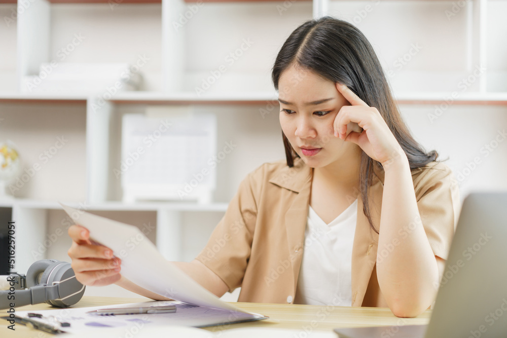 Online lifestyle concept A female home worker seriously concentrating on reading some data from the paper. Online lifestyle concept A female home worker seriously concentrating on reading some data from the paper.