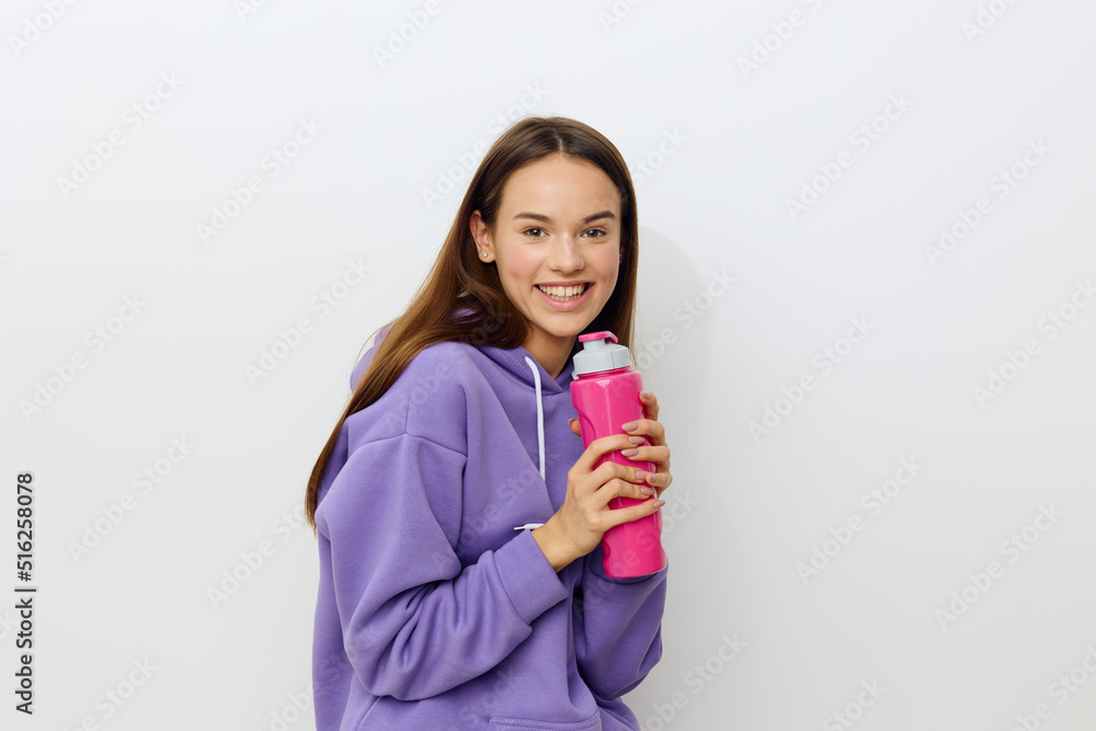 an attractive woman stands on a white background in a purple suit holding a pink bottle clasping it with both hands imagining that it is a microphone an attractive woman stands on a white background in a purple suit holding a pink bottle clasping it with both hands imagining that it is a microphone