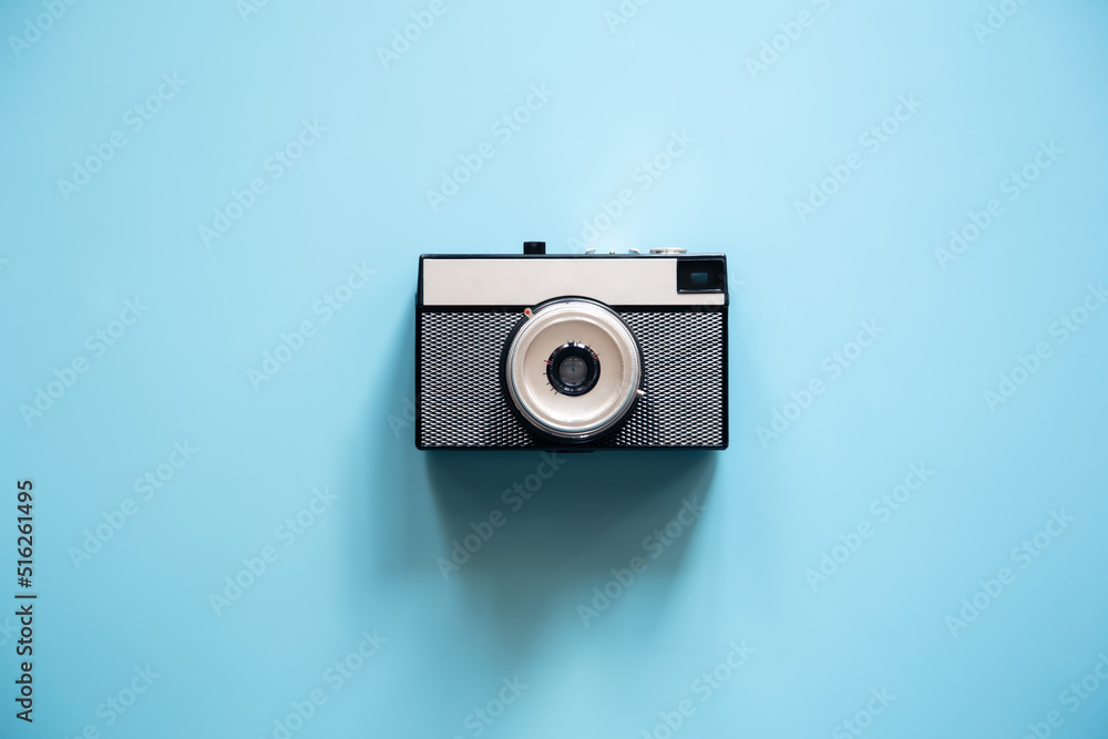 Vintage retro camera on a blue background, flat lay.