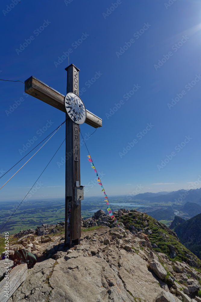 On top, summit cross with Tibetan prayer flags on the Aggenstein in the Tannheim Mountains, Austria