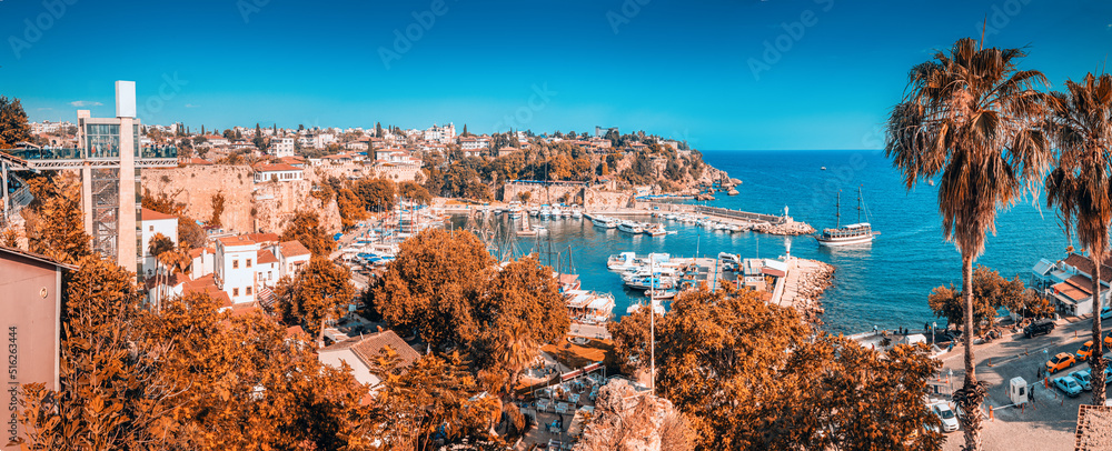 Fototapeta premium tourist cruise ship or yacht is sailing to Antalya old town harbor from open sea. Trip and excursion and vacation in Turkey background