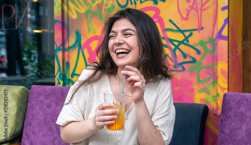 Photography Happy young woman with a glass of lemonade against a bright painted wall