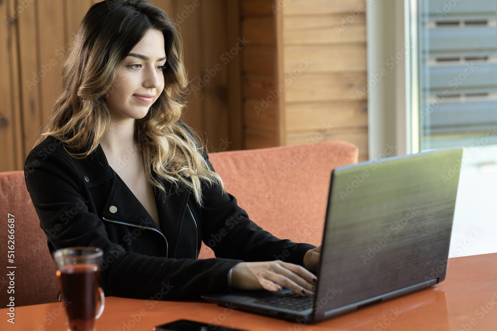 Portrait of young woman sitting in cafe working on laptop, charming freelancer girl thinking about new ideas while working with pc, technology or startup business concept Portrait of young woman sitting in cafe working on laptop, charming freelancer girl thinking about new ideas while working with pc, technology or startup business concept