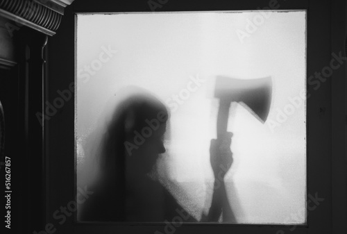 Woman killer with an axe in his hand. Creepy background