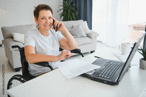 Middle age woman using laptop sitting on wheelchair at home © Serhii