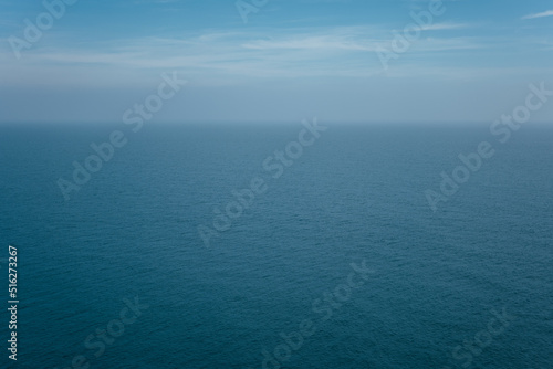 The front view of the sea with morning sky and fuzzy horizon. The ocean deep indigo color in daylight. Feeling calm, cool and relaxing.