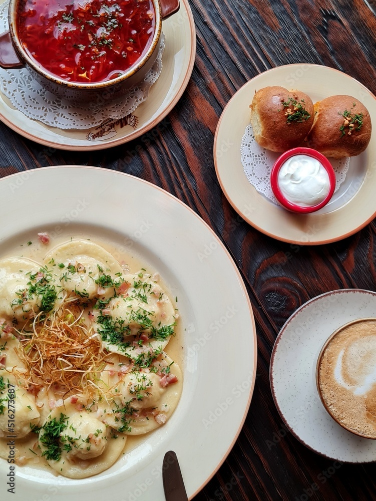 Dishes of Ukrainian cuisine on plates: borscht, donuts and dumplings Dishes of Ukrainian cuisine on plates: borscht, donuts and dumplings