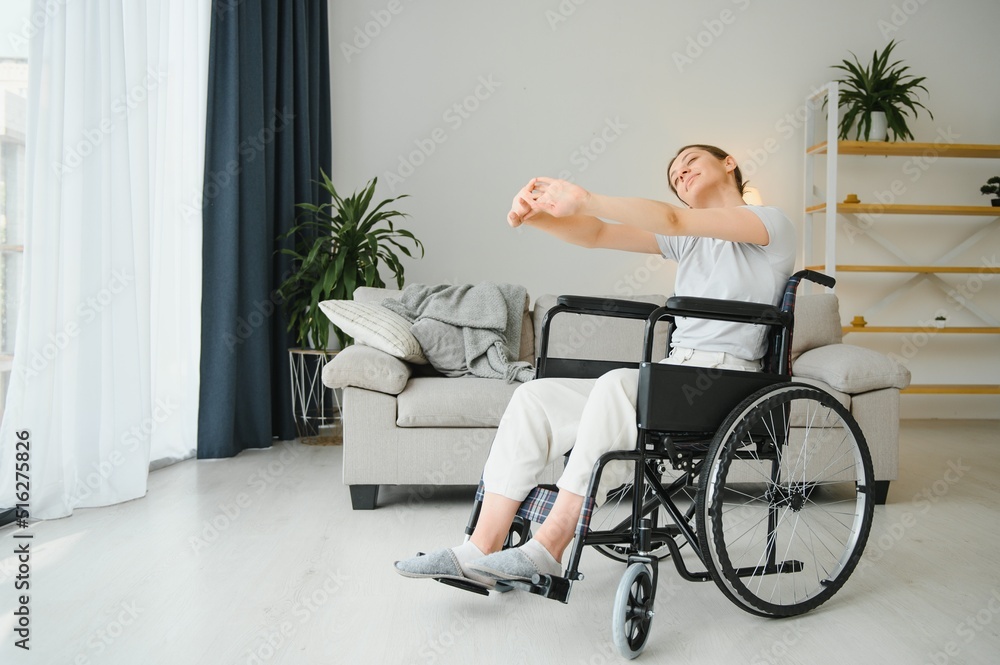 Fototapeta premium Woman in wheelchair working out in living room