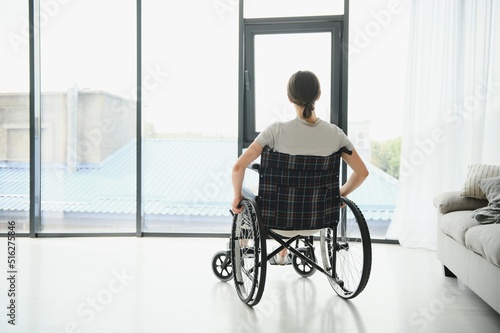 Young woman in wheelchair at home in living room. © Serhii