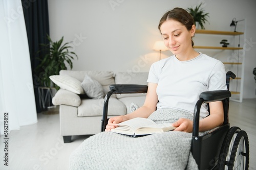 Woman in wheelchair reading book at home