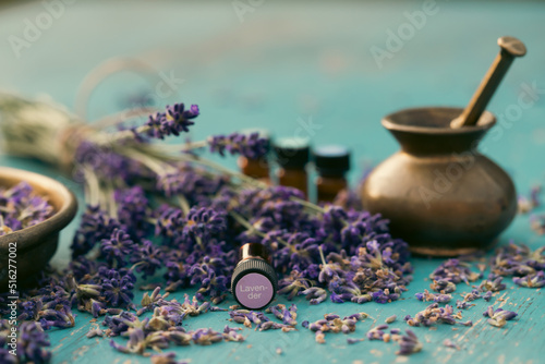 Bottle with aroma oil and lavender flowers on blue background