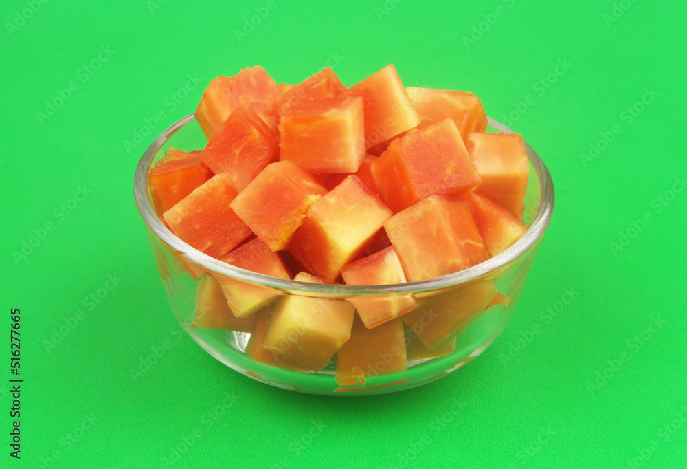 Sliced red papaya fruit in bowl on green background Sliced red papaya fruit in bowl on green background