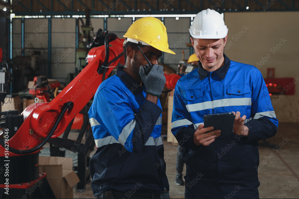 Professional heavy industry technician engineer maintenance and check part of robot arm machine in intelligent factory with computer and walkie talkie. Industrial and technology support system concept Professional heavy industry technician engineer maintenance and check part of robot arm machine in intelligent factory with computer and walkie talkie. Industrial and technology support system concept