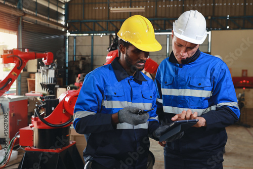 Professional heavy industry technician engineer maintenance and check part of robot arm machine in intelligent factory with computer and walkie talkie. Industrial and technology support system concept © feeling lucky