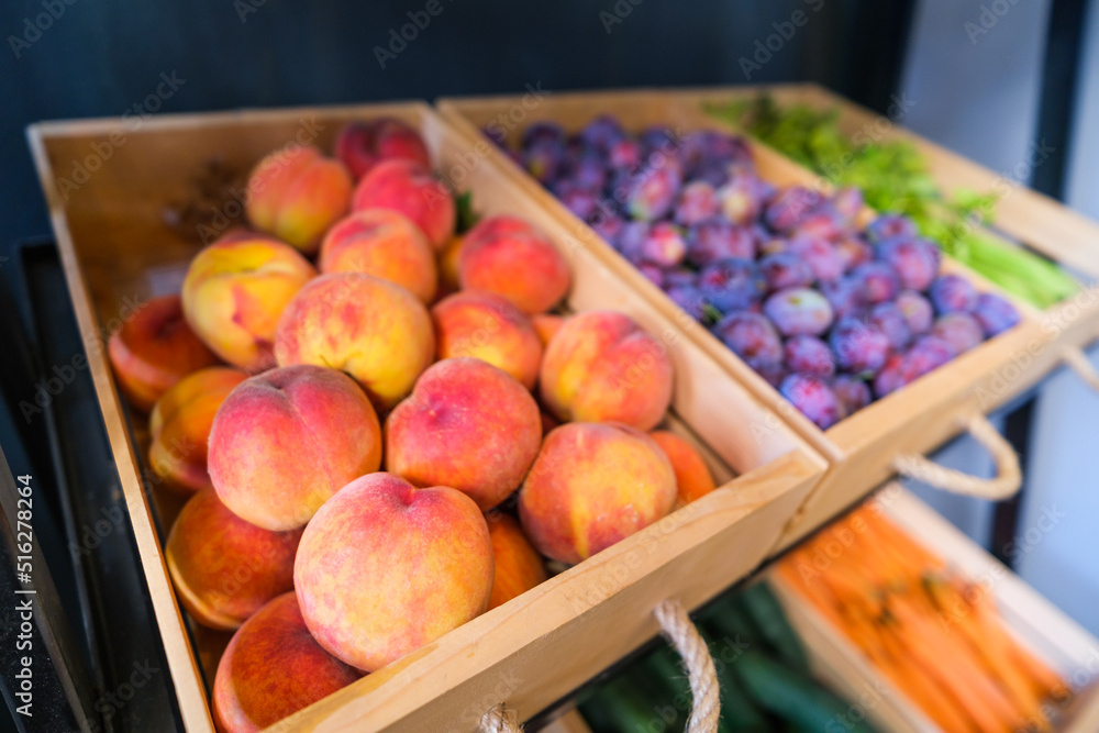 Healthy fruit and vegetables in grocery shop. Close up of basket with peaches in supermarket.