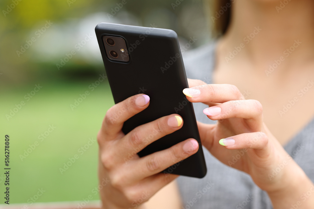 Woman hands close up using smart phone in a park