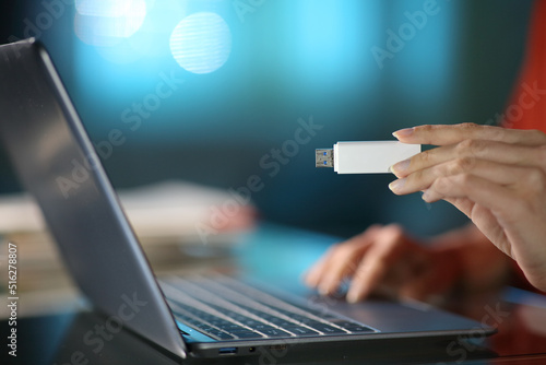 Vászonkép Woman hand holding a pen drive in the night at home