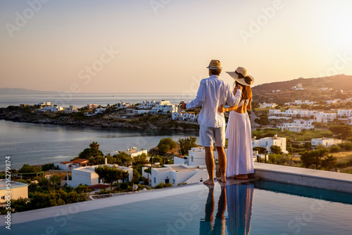 Fotografiet Happy couple on vacation time enjoys the summer sunset over the Aegean Sea by th
