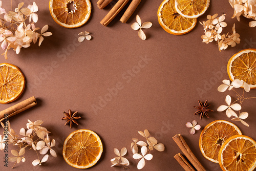 Fototapeta Naklejka Na Ścianę i Meble -  Autumn spice and flowers frame, border on brown background