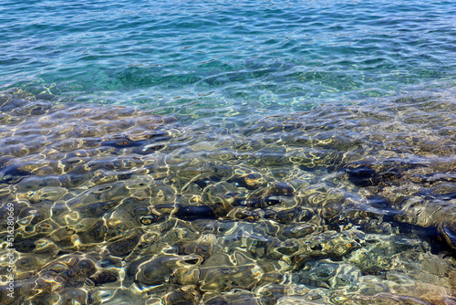 Transparent sea surface with stones on a bottom. Turquoise water for background