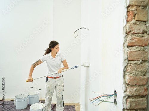 Painter with paint roller doing final painting in apartment photo