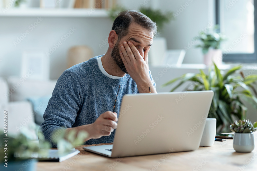 Exhausted businessman sitting with laptop in home office Exhausted businessman sitting with laptop in home office