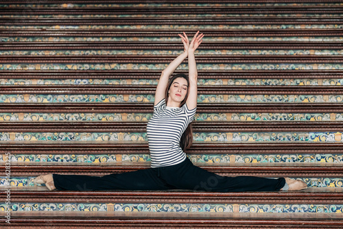 Ballet dancer with arms raised practicing splits on staircase at Plaza de Espana photo