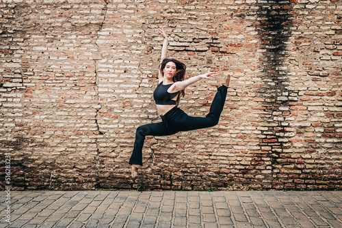 Young ballet dancer dancing in front of brick wall photo